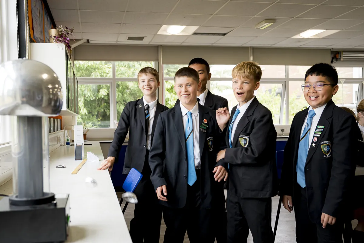 Lyndon School pupils in blazers laughing around a science demonstration in a classroom.